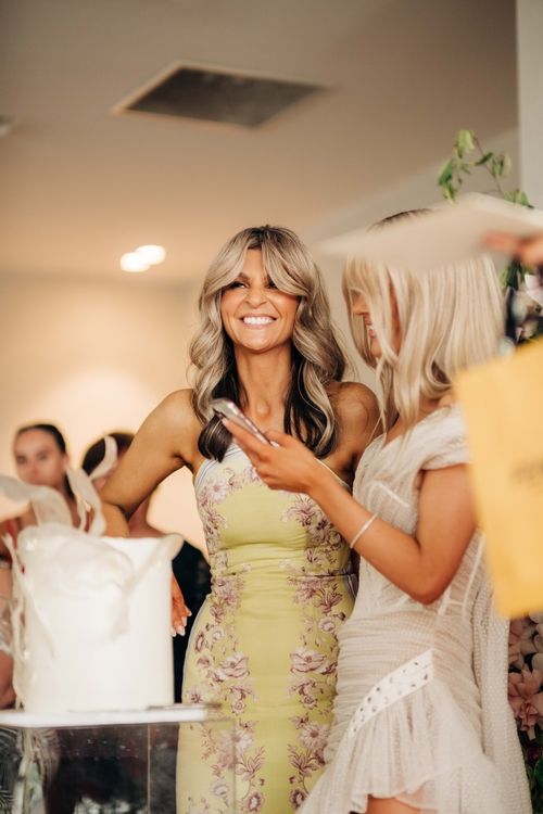 Woman in floral yellow dress smiling at a celebratory event.
