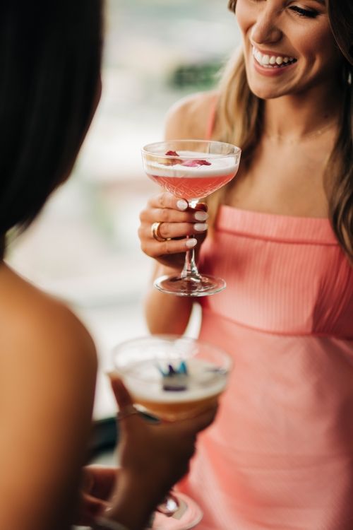 Woman in pink top holding a martini glass while socializing.