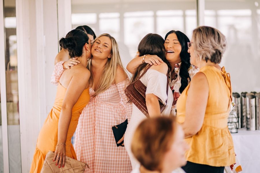 A group of friends sharing an emotional embrace at a celebration event indoors.