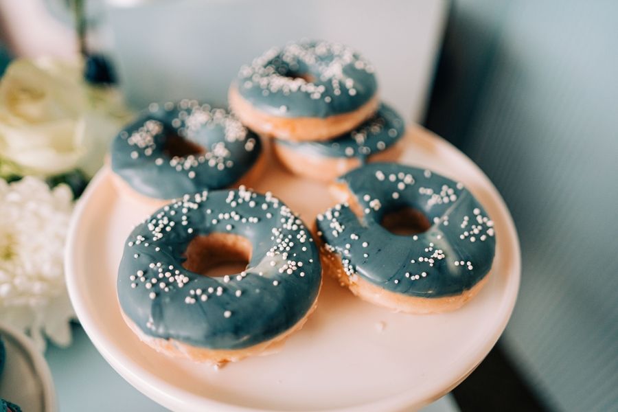 Gray frosted donuts with white sprinkles displayed on white plate.