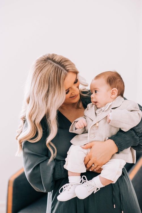 Adult in dark sweater shares tender moment with baby in light colored outfit.