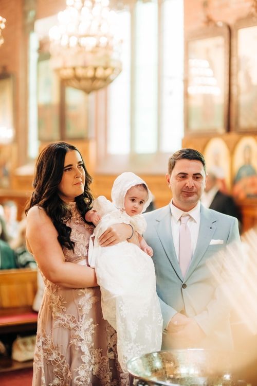 Baptism ceremony in an ornate church with decorative chandeliers and religious icons.