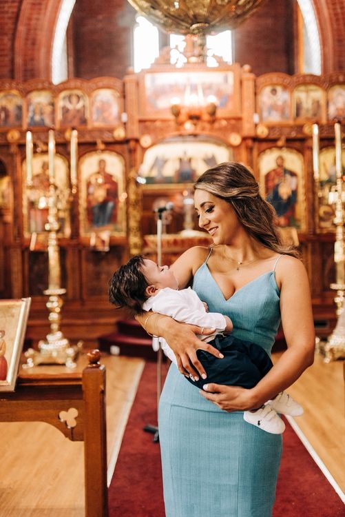 Tender moment captured in an Orthodox church with ornate iconography and candlelit backdrop.