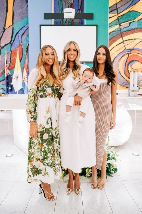 Elegant gathering of women in stylish dresses against a modern artistic backdrop.