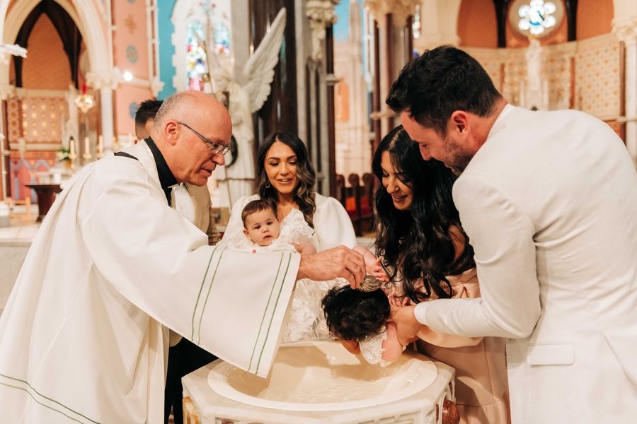 Traditional religious ceremony taking place at the baptismal font in an ornate church.