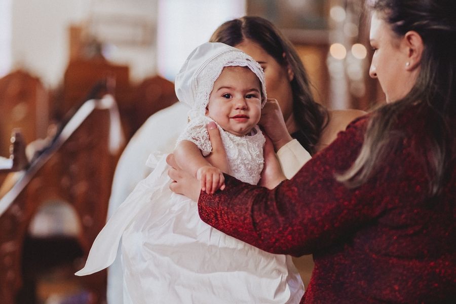 Intimate baptism moment with infant in traditional white christening gown.