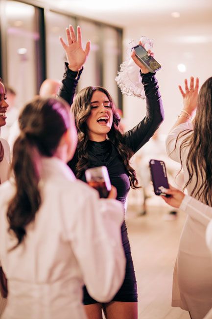 People dancing and celebrating with phones raised at a party.