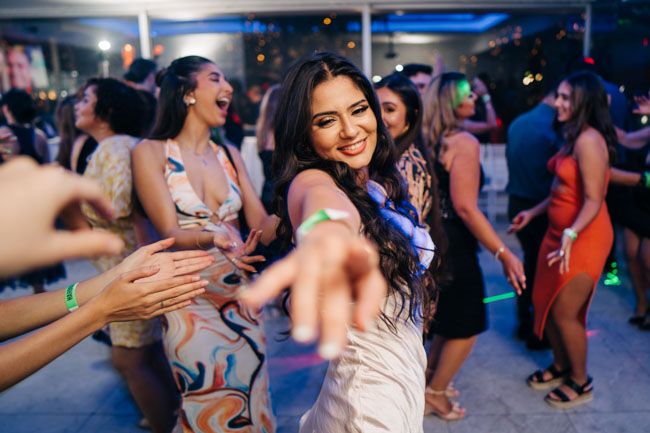 People dancing and having fun at a lively party with colorful lighting.