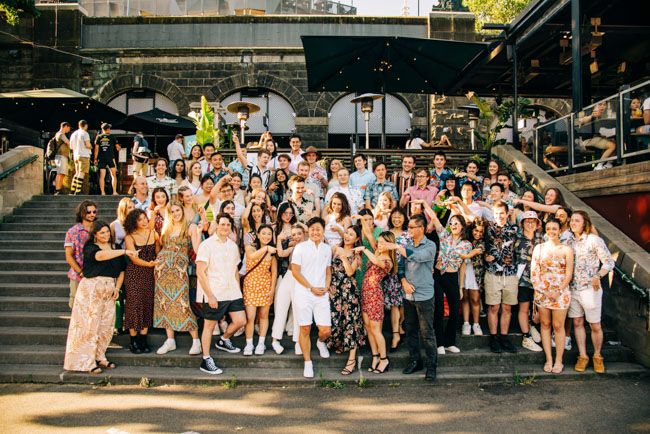 Large group photo of party guests gathered on outdoor steps during daytime.