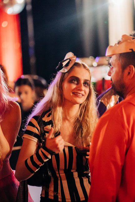 Woman in striped dress enjoying conversation at nighttime event.