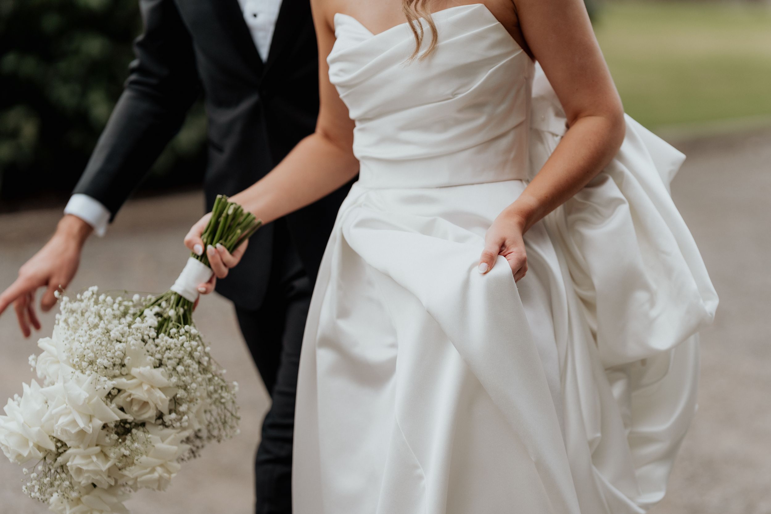 A bride holds a white and green wedding bouquet.