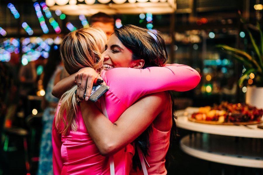 Two people in bright clothing sharing emotional hug at party.