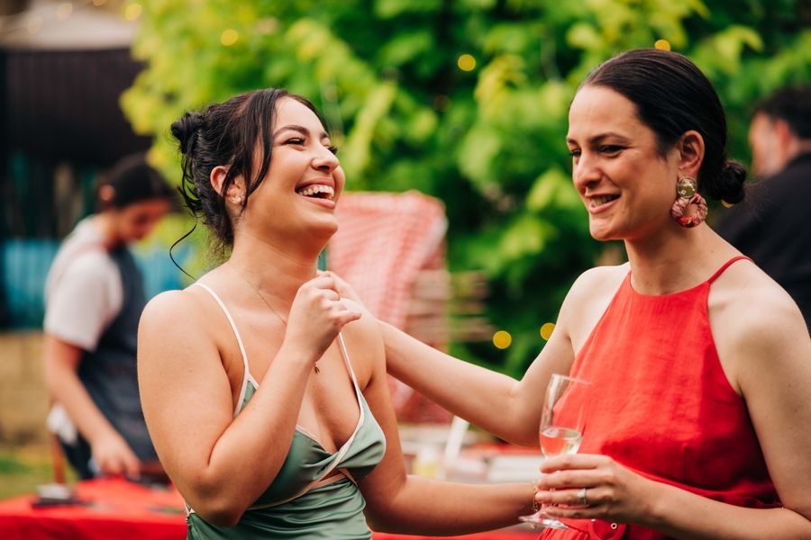 Two party guests laughing together at an outdoor summer event.