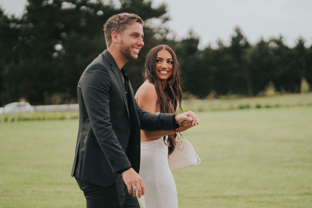 Couple celebrating outdoors on grassy field.