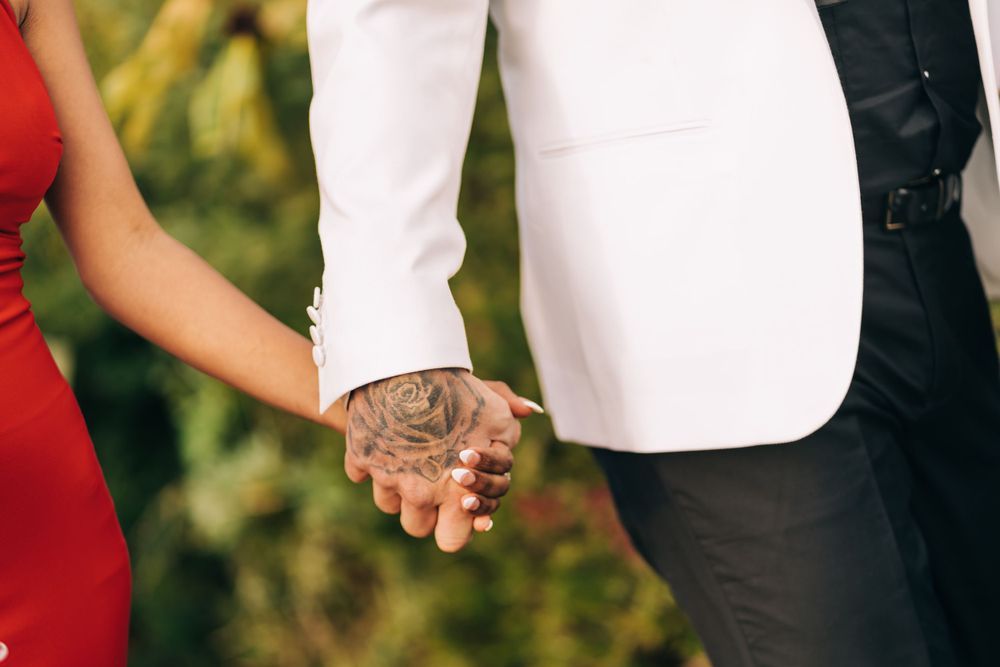 Close up of couple holding hands showing engagement ring.