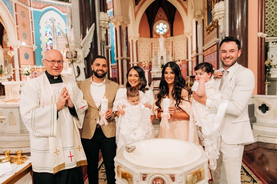 A group gathers around a baptismal font in an elaborate church interior.