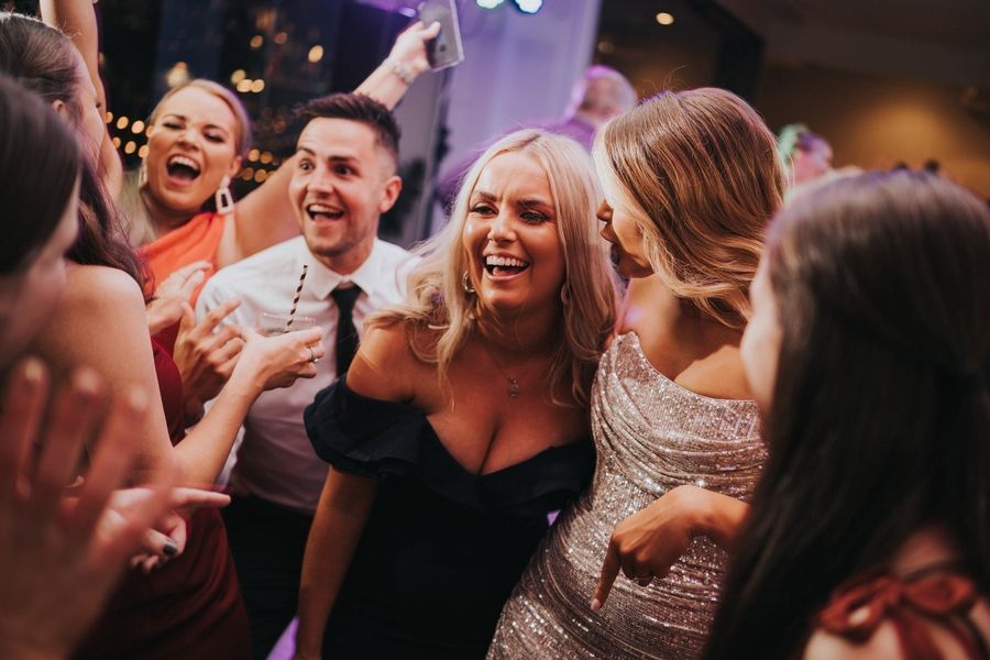 A group of party guests laughing and celebrating together at a lively indoor event.