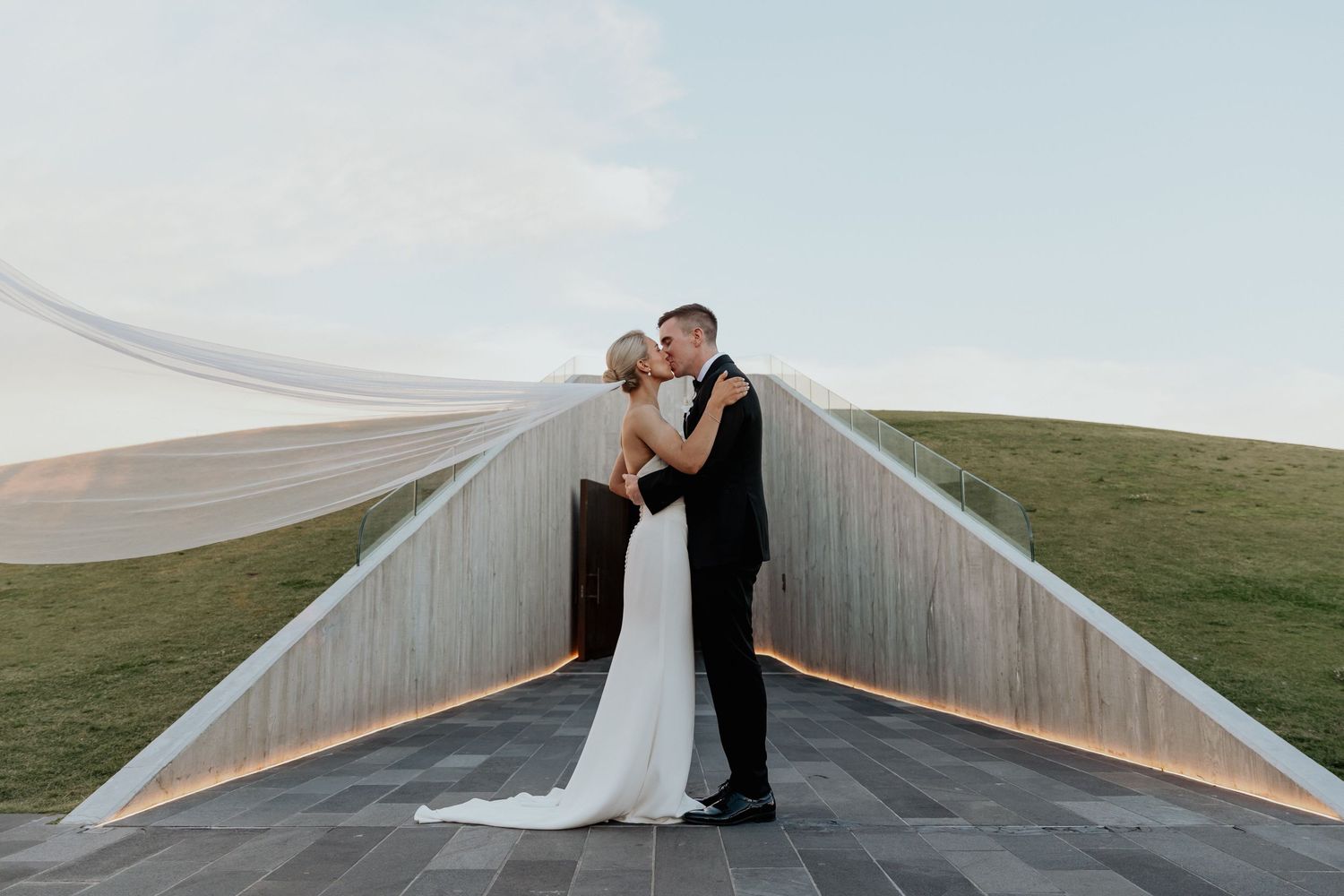 A couple embrace in a candid wedding portrait outdoors.
